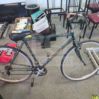 Bridgestone XO-5 hybrid bicycle, green frame, 700c wheels, drop handlebars, visible wear. Suitable for versatile cycling.