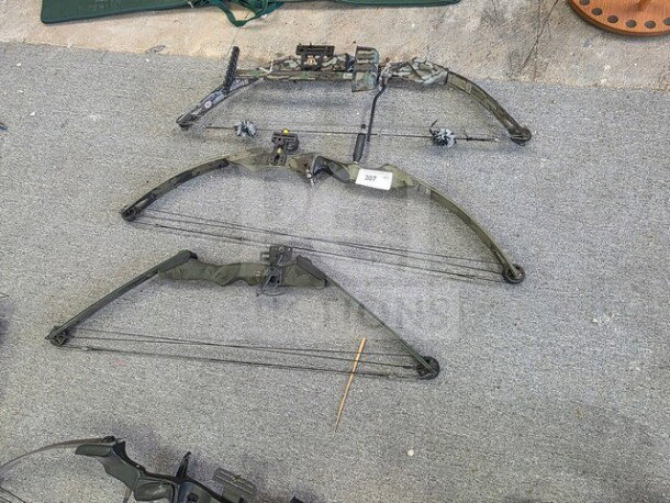 Lot of 3 compound bows, camo design, featuring pulleys and cables. Includes sight, stabilizer, in used condition. Item tag 307.