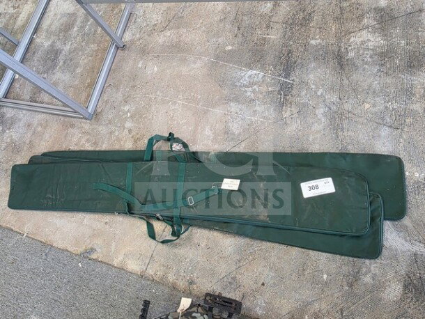 One lot of green Bowflag carrying cases, showing straps and attached tags with number 308, laid on concrete surface.