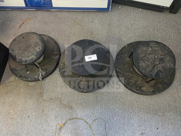 Lot of 3 black weighted umbrella stand bases, used condition, visible wear and dirt, one base with a chain. Tag marked "320."