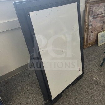 Black-framed standing dry erase board, rectangular, lightly used, suitable for signs or messages.