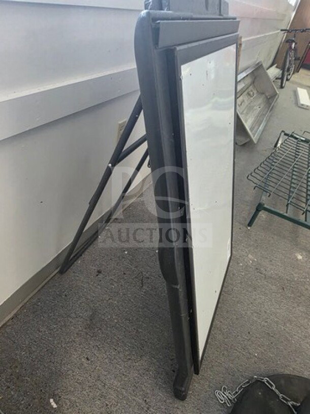 Adjustable black frame dry erase board, slightly used, freestanding design, suitable for indoor signage or presentations.