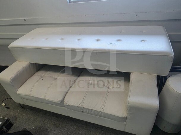 Lot of white club furniture including a tufted bench and sofa. Shows signs of wear. Ideal for club or lounge decor.