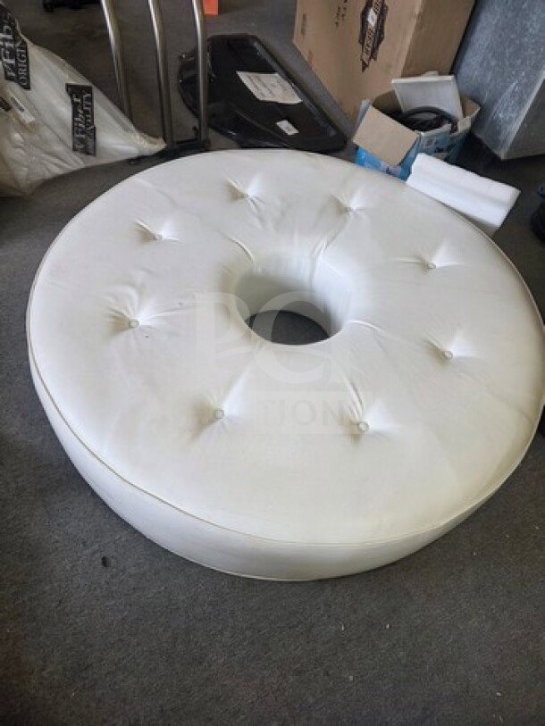 White circular tufted ottoman from a club, donut shape, used condition, ideal for modern interiors.