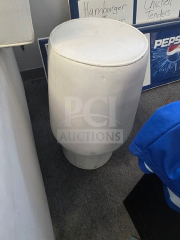 White cylindrical furniture piece from a club, padded top, minor wear, suitable for seating or decor.