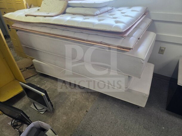 Lot of white club furniture including padded bench seating with tufted upholstery. Stackable pieces, good condition.