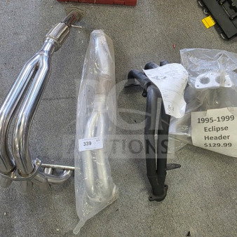 Lot of miscellaneous exhaust headers, including chrome and black metal models. One labeled "1995-1999 Eclipse Header $129.99."