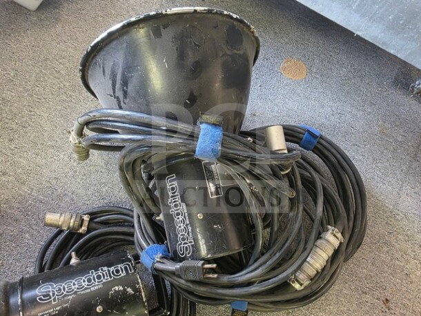 Pair of Speedotron Universal Light Units, visible wear, tangled cables, sold as is. Branding and connectors shown.