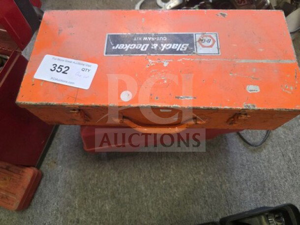 Orange Black & Decker tool box with handle, scuffed surface, labeled "OUT-SAW KIT." Auction tag "352" visible.