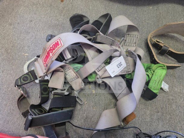 Lot of miscellaneous safety harnesses, featuring Simpson branded straps. Includes various buckles and tags visible. Good condition.