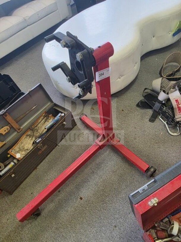 Red 360-degree rotating engine stand for disassembly and repair, features a sturdy frame and casters. Sold as is.