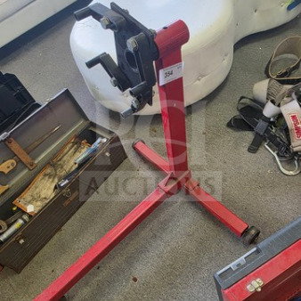 Red 360-degree rotating engine stand for disassembly and repair, features a sturdy frame and casters. Sold as is.