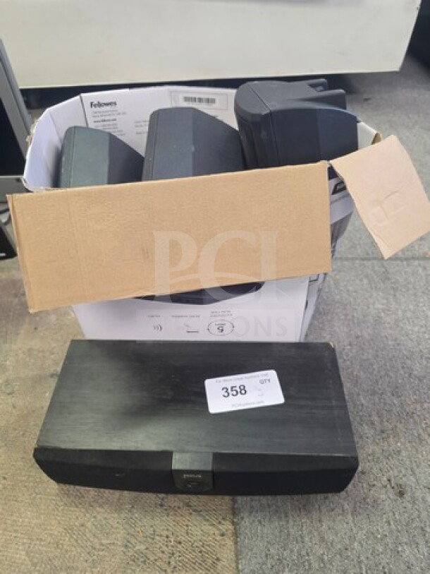 Lot of miscellaneous electronics, including speakers in a cardboard box and a labeled black electronic device. Moderate condition.