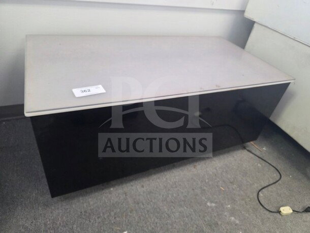 Modern desk with light grey tabletop and black base, minimal wear. Visible tag labeled "362."