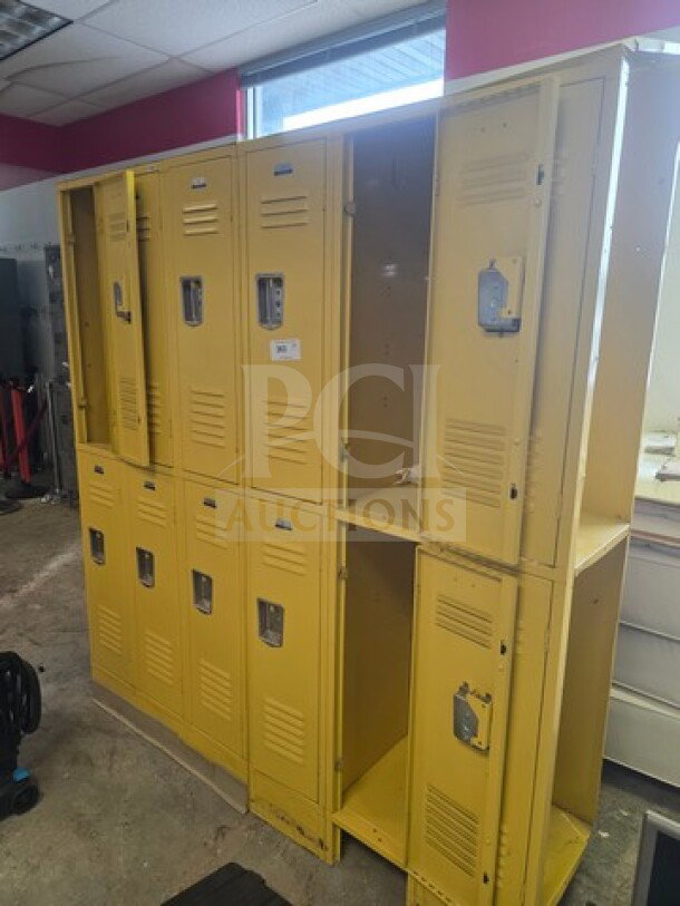 Yellow lockers, multiple units, used condition. Visible wear and minor dents. Ventilation slots and padlock hasps on each door.
