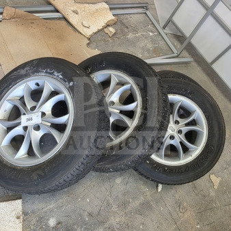 Lot of 4 Goodyear P195/70R15 tires with rims, used condition, shown on a warehouse floor. Sold as is.