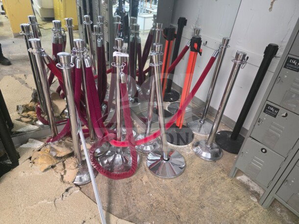 Lot of crowd control stanchions with red and black ropes, chrome finish, various conditions, suitable for event management.