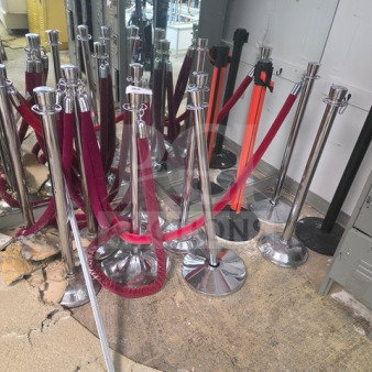 Lot of crowd control stanchions with red and black ropes, chrome finish, various conditions, suitable for event management.