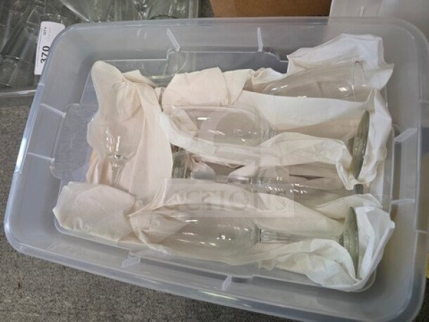 Lot of miscellaneous champagne glasses in a storage bin, wrapped in tissue for protection, condition appears good.
