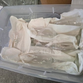 Lot of miscellaneous champagne glasses in a storage bin, wrapped in tissue for protection, condition appears good.