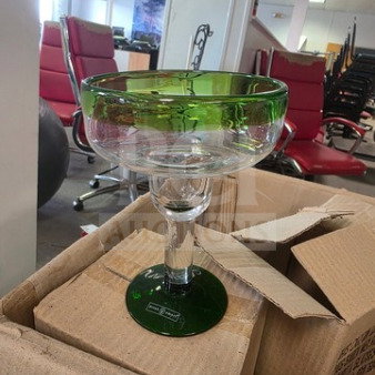One lot of green-rimmed margarita glasses, clear glass, pristine condition, stacked in cardboard box, suitable for parties.