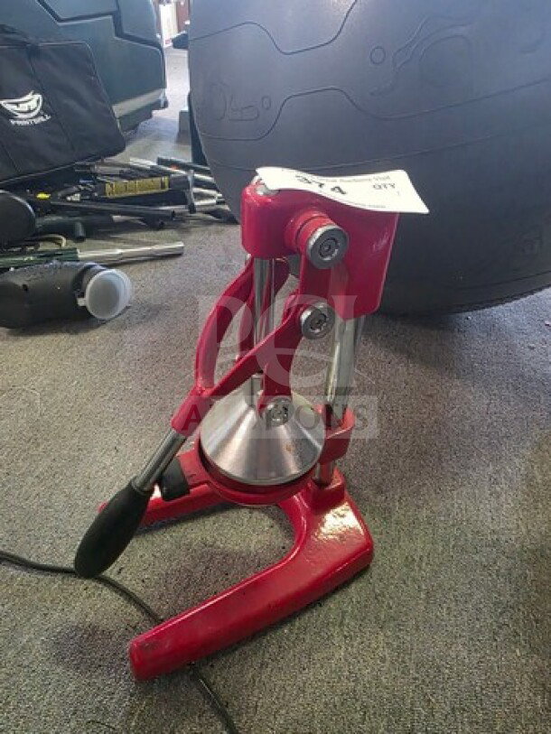 Red manual citrus juicer with a sturdy metal press and lever, in good condition. Appears durable for efficient juicing.