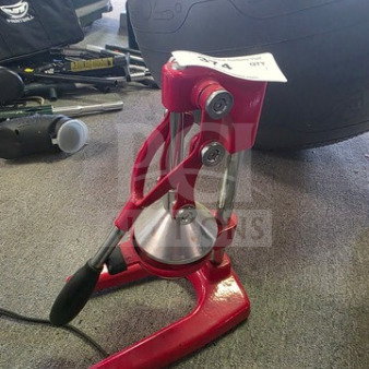 Red manual citrus juicer with a sturdy metal press and lever, in good condition. Appears durable for efficient juicing.