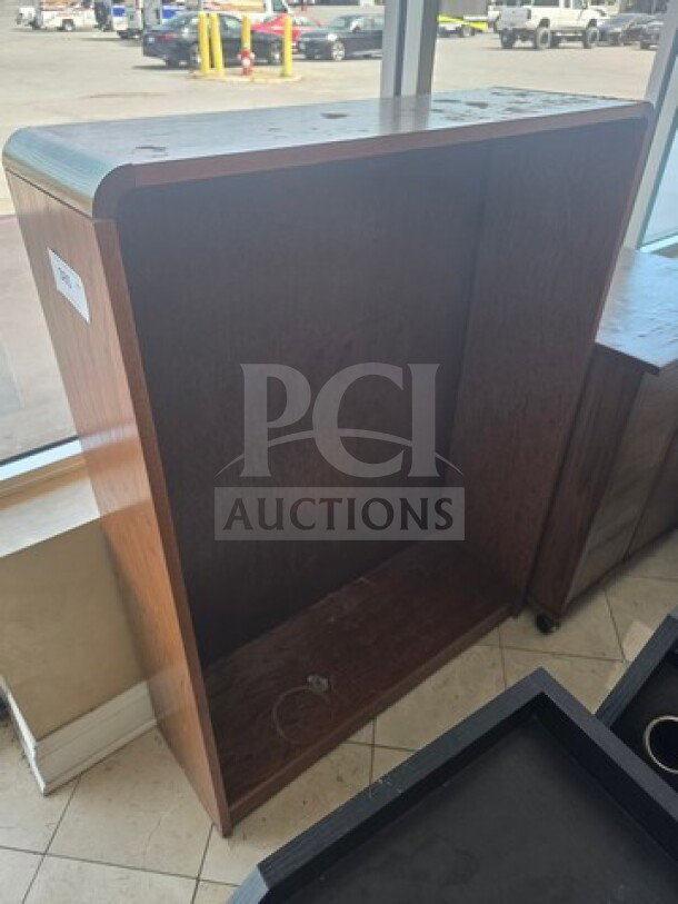 Wood host station with smooth finish, open front design, and sturdy build. Minor scuffs visible, ideal for restaurant use.