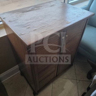 Wooden cabinet with two doors, metal handles, and a smooth top. Light wear visible, compact size suitable for small spaces.