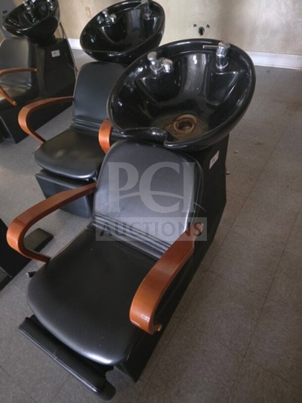 Black shampoo chair backwash unit with round basin, sleek design, and wooden armrests. Good condition, ideal for salons.