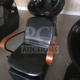 Shampoo chair backwash unit with black upholstery, wooden armrests, and integrated basin. Good condition.