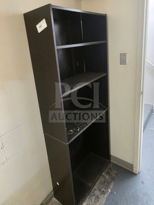 Lot of 2 tall black bookcases, four shelves each, used condition with visible wear.