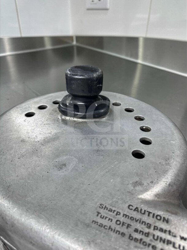 Nutrifaster N450 juicer lid with a warning label on heavy-duty stainless steel surface, showcasing robust construction.