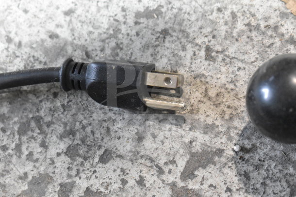 Black power plug for a 2025 Bizerba Commercial Meat Slicer, 120 Volts, 1 Phase, shown against a gray surface.