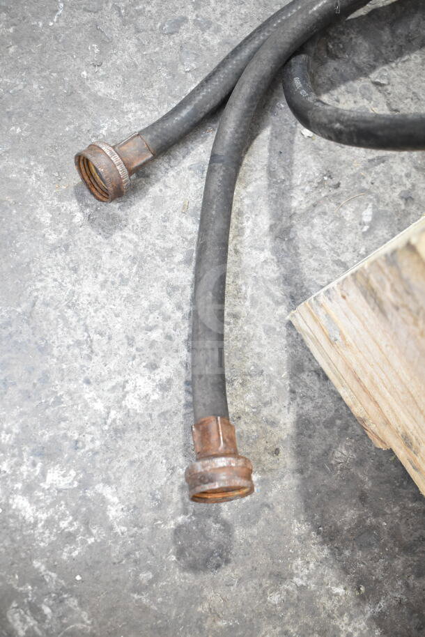 Rubber hoses on concrete, likely for a Taylor soft serve ice cream machine. Hoses appear worn and corroded at fittings.