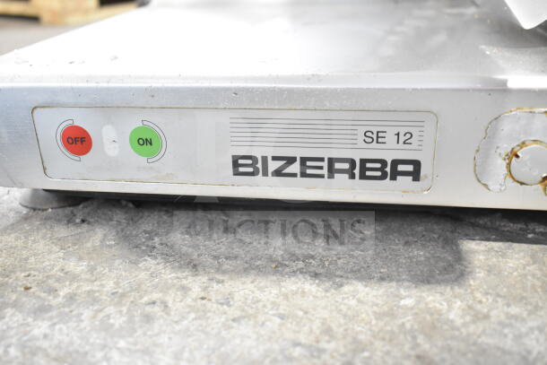 Bizerba SE 12 U meat slicer with power switch, shows on/off buttons. Model tag indicates commercial use, 120V, 1 Phase.