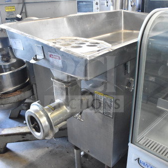 Commercial floor-style meat grinder, stainless steel, large tray, used condition. Safety and operation warning labels visible.