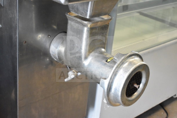 Commercial floor-style meat grinder in stainless steel, showing feed chute and grinding plate; used condition.