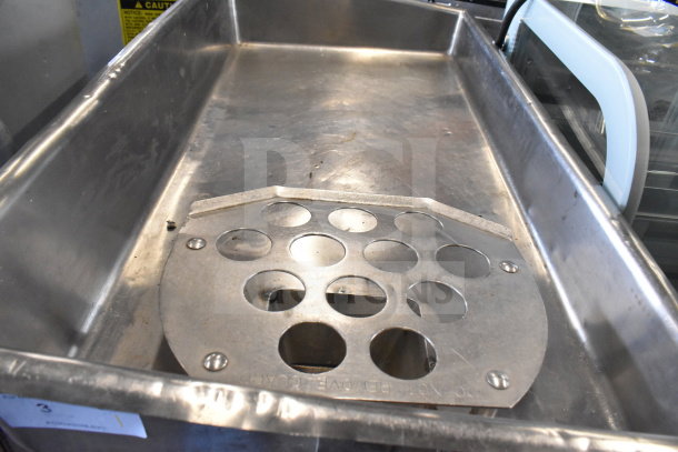 Commercial floor-style meat grinder in stainless steel, showing grinding plate with multiple holes, appears in used condition.
