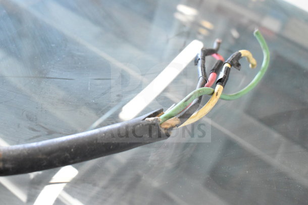 Damaged wiring of a commercial floor-style meat grinder, showing exposed colored wires needing repair.