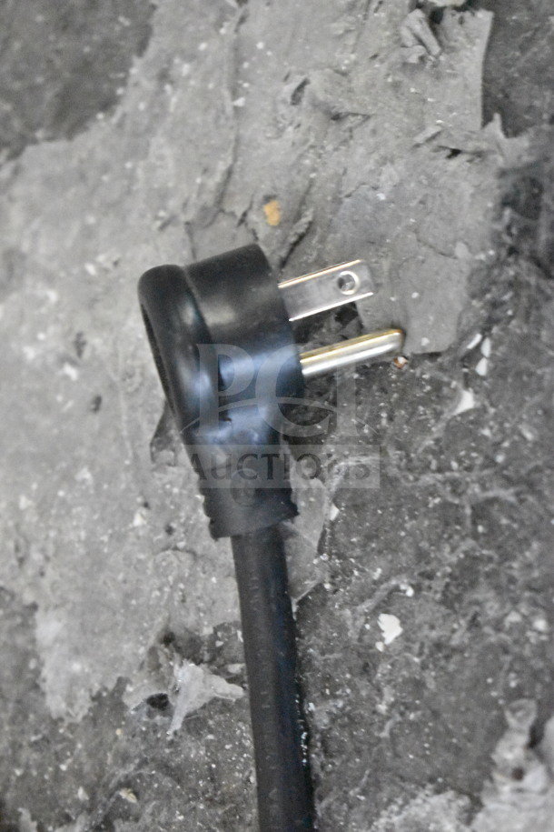 Close-up of a black power plug on concrete, part of the 2018 True GDM-49-HC cooler, 115 volts, tested and working.