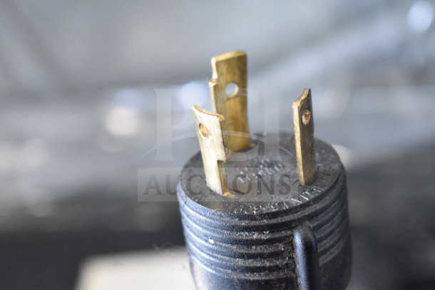 Close-up of a plug for a Schaerer Barista espresso machine, showing prongs and markings.