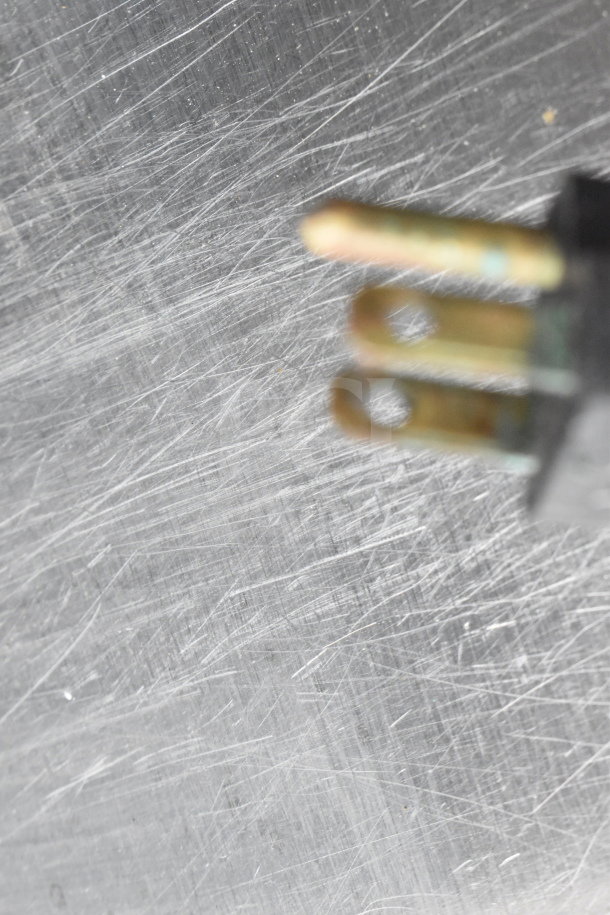 A close-up view of a metal surface with visible scratches and part of an electrical plug.