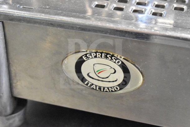 Faema E61 espresso machine close-up, showing "Espresso Italiano" logo. Features stainless steel body.