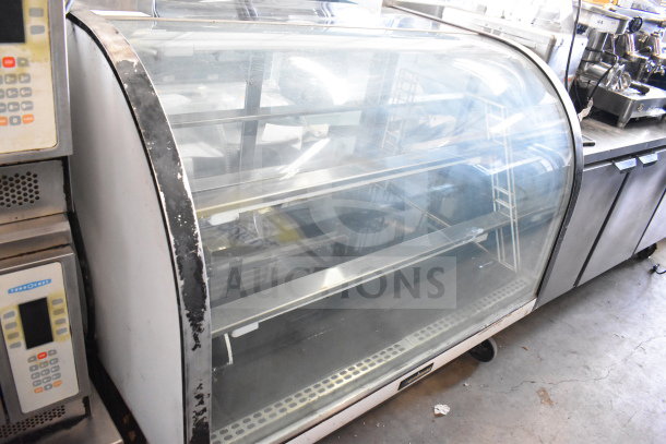 Delfield Commercial Floor Style Deli Display Case, curved glass front, built-in shelving, visible wear on frame, good condition.