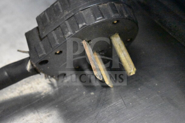 Black power plug of Turbochef NGC commercial rapid cook oven, showing prongs and wear marks. Uses 208/240 volts, 1 phase.