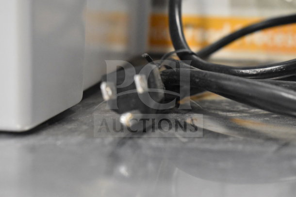 Close-up of a power cord for the Robot Coupe R2 Commercial Countertop Food Processor, indicating electrical connection.
