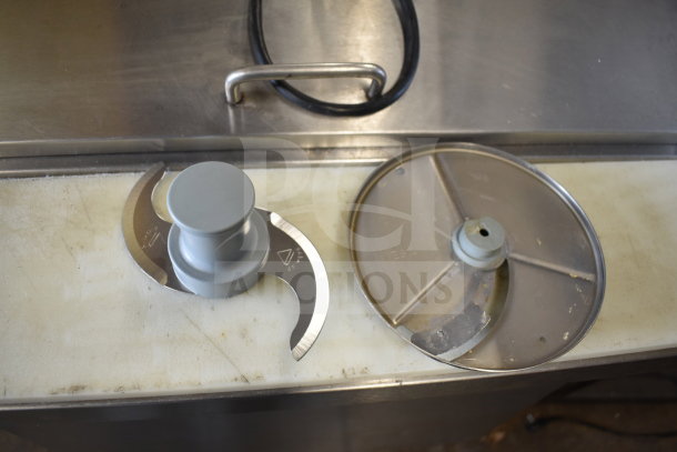Robot Coupe R2 food processor blades on countertop, metal and plastic parts visible, used condition.