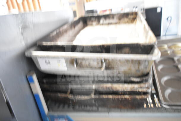Stacked metal roasting pans and two bun baking pans, used condition. Auction lot offers 7 items multiplying bid value.