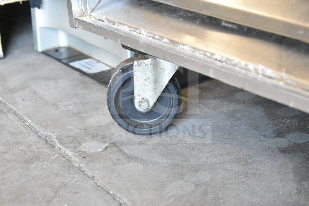 True T-23F freezer caster wheel, part of the commercial refrigerator setup. Visible signs of use, sturdy design.